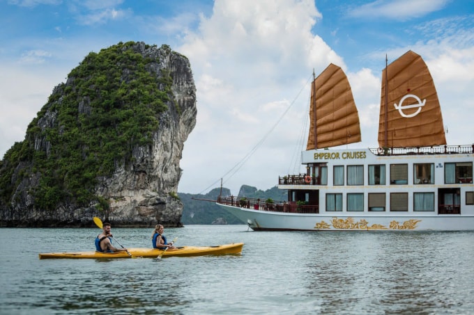 Du khách quốc tế chèo thuyền bên cạnh tàu Emperor Cruises khi chưa bị hư hỏng vì bão Yagi. Ảnh: Lux Group