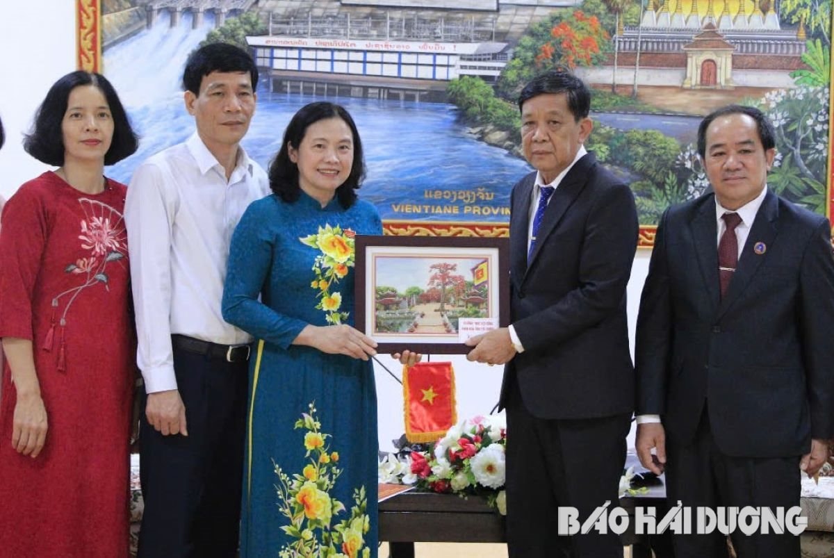 Ảnh trang 2: Đồng chí Nguyễn Thị Ngọc Bích trao gửi món quà là bức tranh phong cảnh Văn miếu Mao Điền cho lãnh đạo tỉnh Viêng Chăn