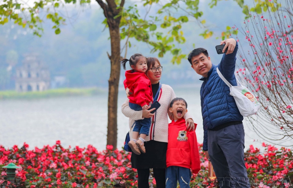 A family captures a springtime moment together by Hoan Kiem Lake in Hanoi (January 2023). (Photo: Thanh Tung – VNA)