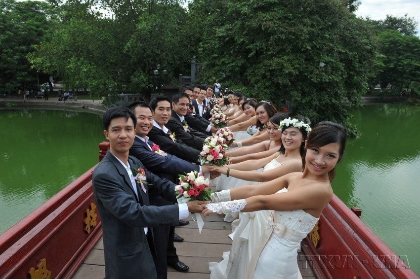 Fifty couples from across the country pose for a group wedding photo at Hoan Kiem Lake in Hanoi. (Photo: VNA)