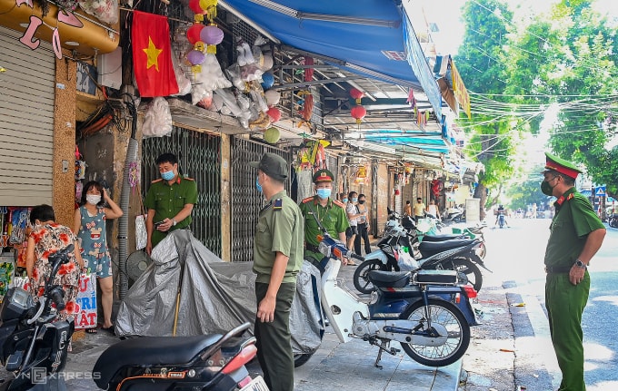 Công an phường tại Hà Nội nhắc nhở các cửa hàng trong thời gian giãn cách dịch Covid-19. Ảnh: Giang Huy