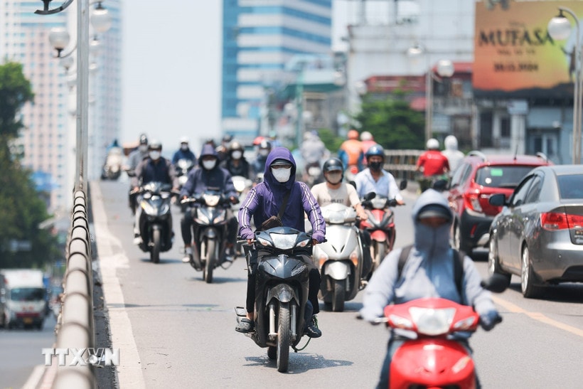 Khẩu trang, áo chống nắng là những thứ không thể thiếu của người dân khi tham gia giao thông trong ngày nắng nóng. (Ảnh: Lê Đông/TTXVN)