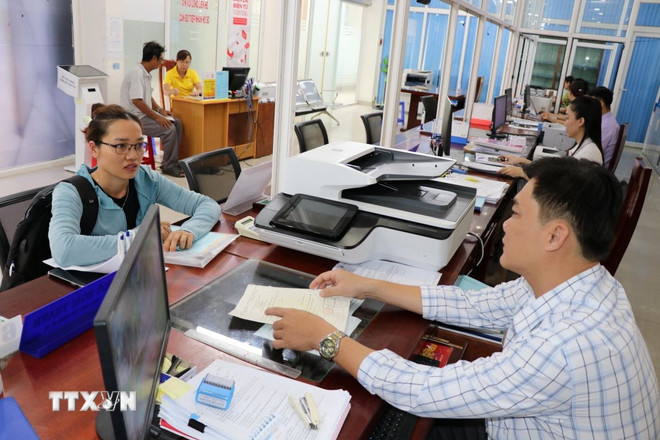 Người dân thực hiện thủ tục hành chính tại Trung tâm Phục vụ hành chính công phường Trà Vinh. (Ảnh: Thanh Hòa/TTXVN) ttxvn-chinh-quyen-dia-phuong-hai-cap-0608-2.jpg