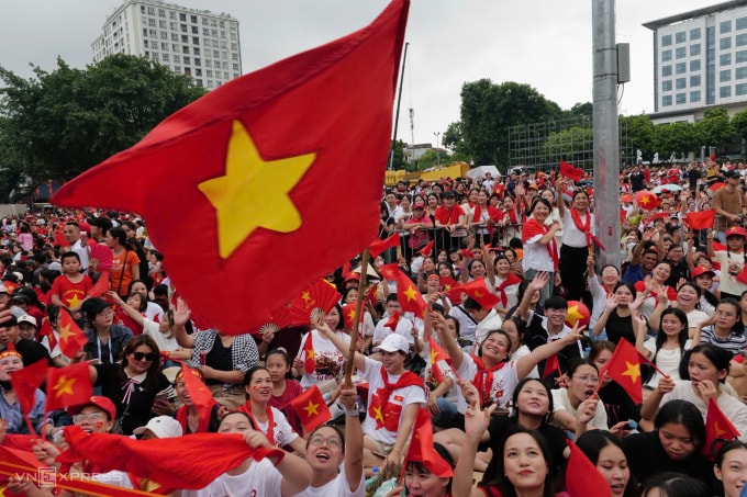 People holding national flags welcome the parade and march near Ba Dinh Square. Photo: Ngoc Thanh