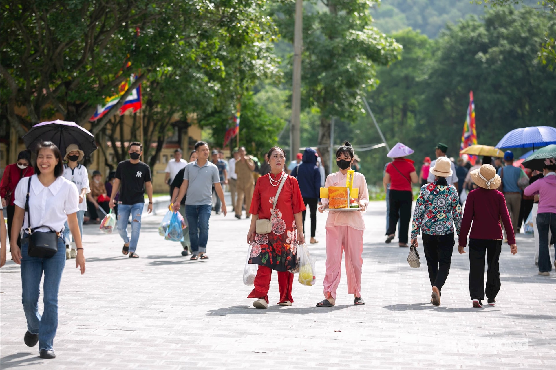 Trên tay là nén hương thơm, bó hoa tươi, nhiều người trong trang phục chỉnh tề thành kính tiến vào đền.