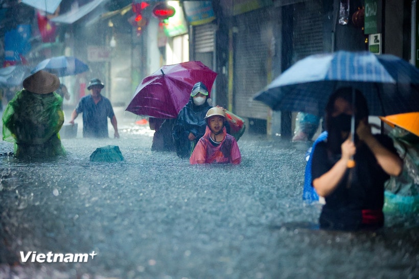 Người dân Thủ đô bì bõm lội nước dưới cơn mưa cực lớn trong ngày 30/9/2025. (Ảnh: Hoài Nam/Vietnam+)