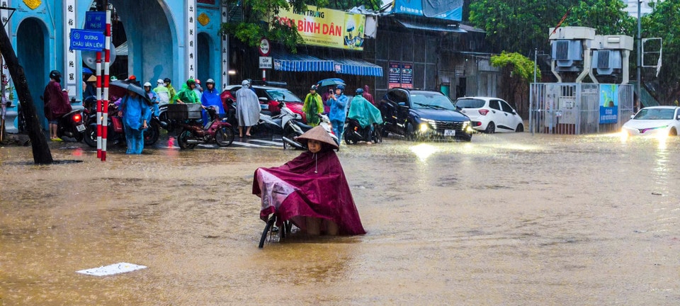 Người dân chật vật di chuyển qua điểm ngập. (Ảnh: Hoài Nam/Vietnam+)