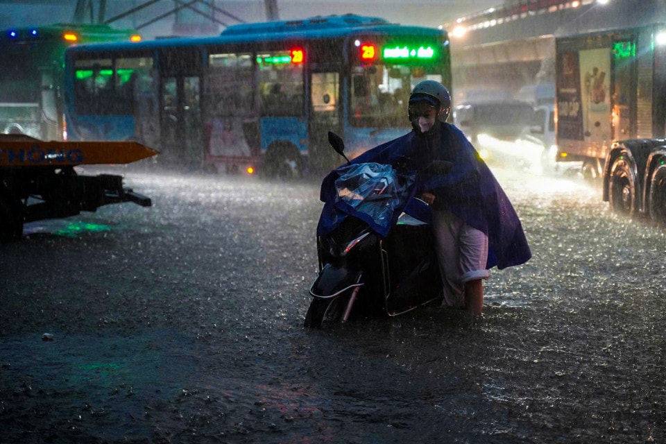 Người dân chật vật di chuyển qua các điểm ngập úng. (Ảnh: Hoài Nam/Vietnam+)