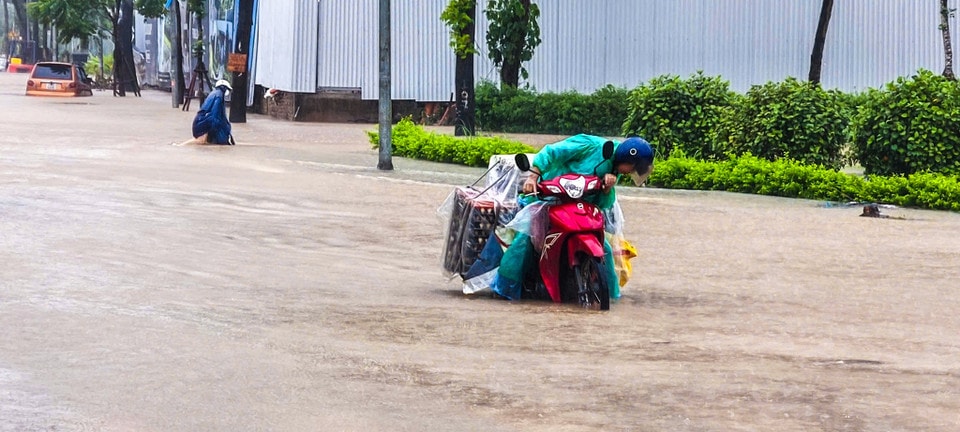 Người dân chật vật di chuyển qua điểm ngập. (Ảnh: Hoài Nam/Vietnam+)