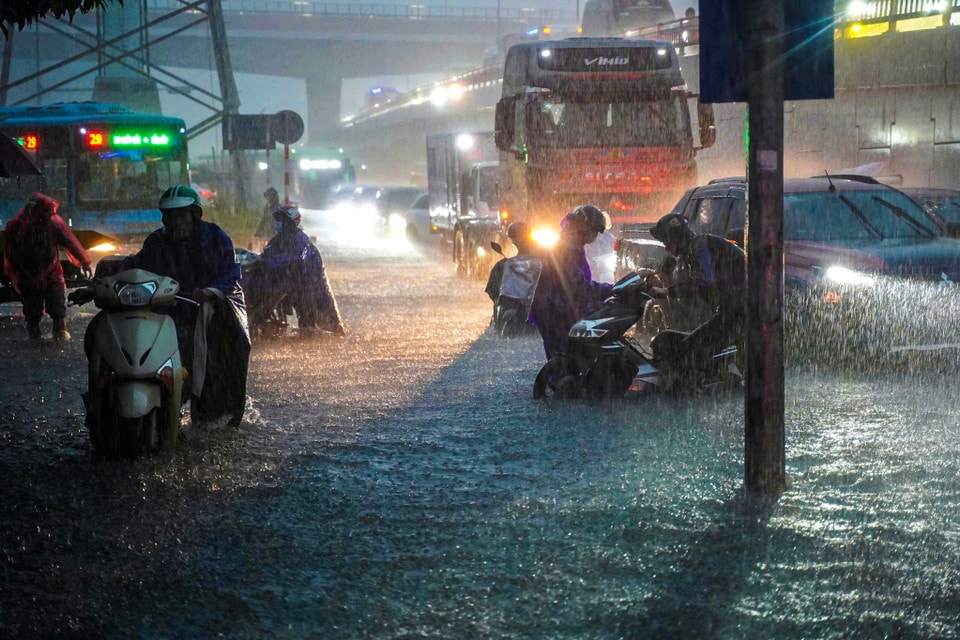 Người dân chật vật di chuyển qua các điểm ngập úng. (Ảnh: Hoài Nam/Vietnam+)
