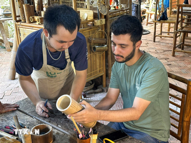 Khách du lịch quốc tế trải nghiệm làm sản phẩm thủ công tại các điểm du lịch thành phố Đà Nẵng. (Ảnh: Trần Lê Lâm/TTXVN) ttxvn-lang-cam-thanh-da-nang-2.jpg