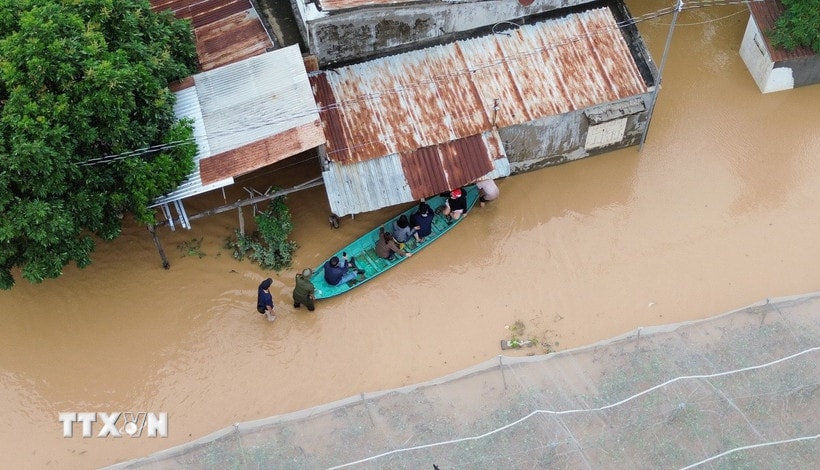 Người dân di chuyển bằng thuyền tại khu vực ngập nước tại xã Ninh Phước (Khánh Hòa). (Ảnh: Nguyễn Thành/TTXVN)