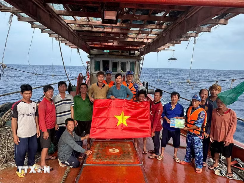 Lực lượng chấp pháp trên biển trao cờ tổ quốc và tuyên truyền IUU cho ngư dân đang đánh bắt trên biển. (Ảnh: Hoàng Nhị/TTXVN)