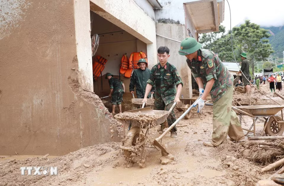 Lực lượng Quân đội giúp dân hót bùn đất, đá trôi vào nhà tại xã Mường Than. (Ảnh: Quý Trung/TTXVN)