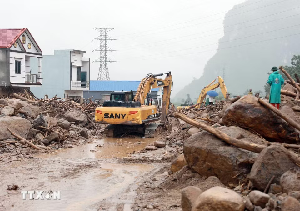 Các phương tiện máy móc tập trung san gạt cây cối, đất đá góp phần thông đường tạm thời cho nhân dân đi lại. (Ảnh: Quý Trung/TTXVN)