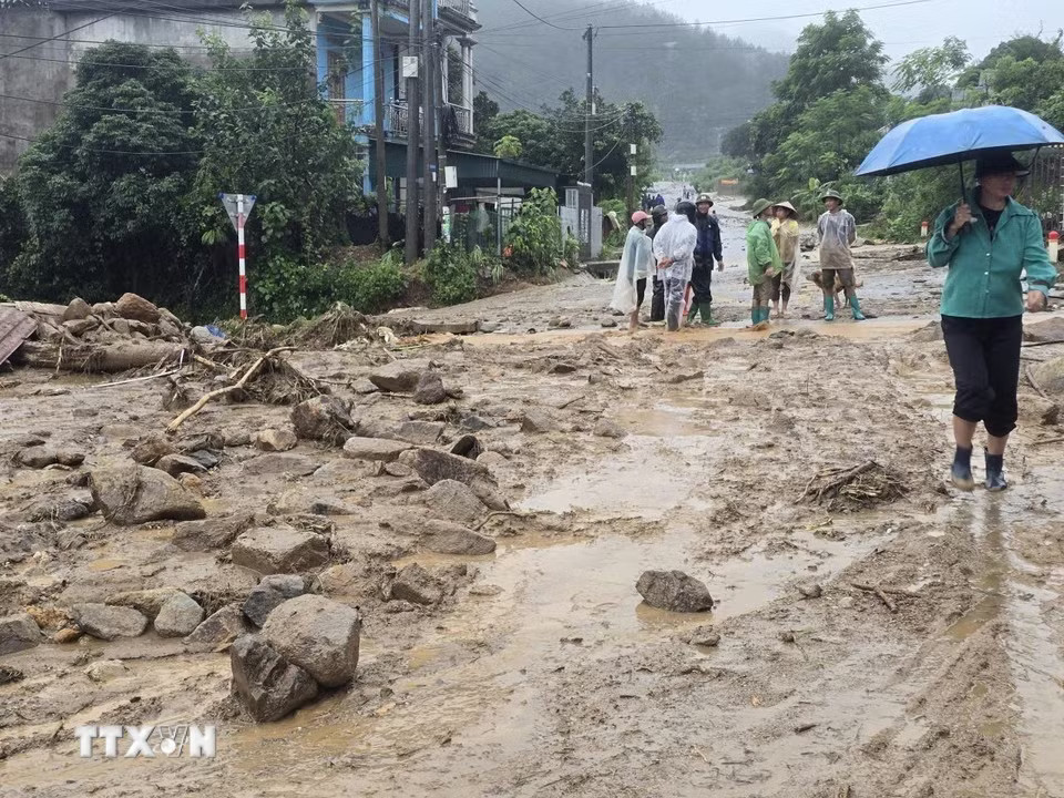 Các phương tiện máy móc tập trung san gạt cây cối, đất đá góp phần thông đường tạm thời cho nhân dân đi lại. (Ảnh: Quý Trung/TTXVN)