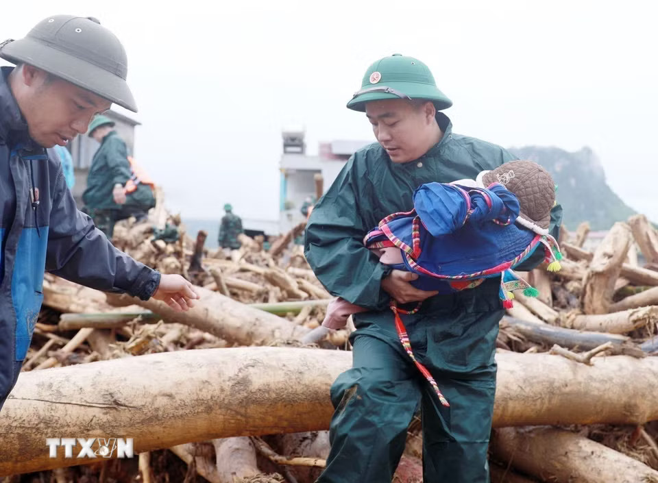 Lực lượng dân quân tựu vệ đưa trẻ em ra khỏi nơi nguy hiểm tại khu vực xảy ra lũ quét xã Mường Than, tỉnh Lai Châu. (Ảnh: Quý Trung/TTXVN)