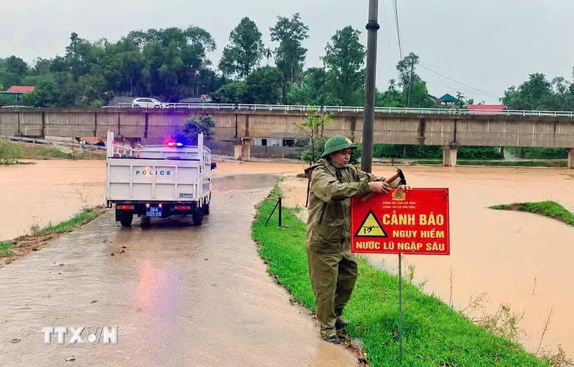 Lực lượng chức năng cắm biển báo ở cung đường ngập lụt. (Ảnh: Công Tường/TTXVN)