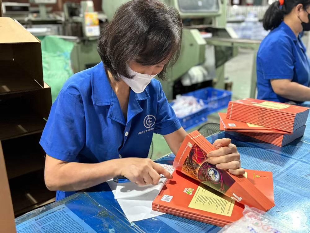 Công nhân thực hiện công đoạn dán tem cho sách giáo khoa. (Ảnh: Phạm Mai/Vietnam+) sach-giao-khoa-5526.jpg