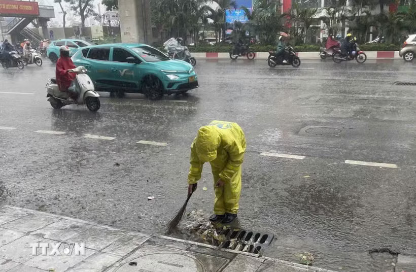 Công nhân công ty thoát nước vớt rác để tiêu thoát nước nhanh. (Ảnh: Nguyễn Thắng/TTXVN)