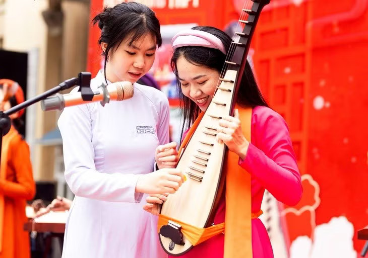 Nữ sinh Trường Trung học phổ thông Trần Phú (Hà Nội) thích thú khi lần đầu tiên được chạm tay vào đàn tì bà. (Ảnh: Vietnam+)
