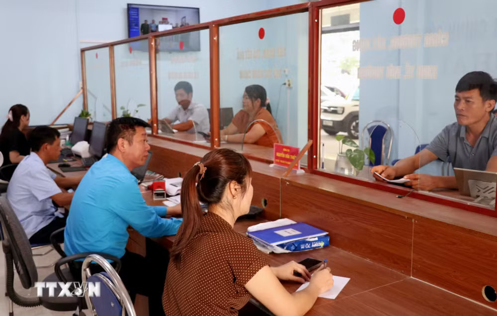 Cán bộ Trung tâm Phục vụ hành chính công xã Lao Chải (Tuyên Quang) hướng dẫn, giải quyết thủ tục hành chính cho người dân. (Ảnh: Đức Thọ/TTXVN) ttxvn-2708-tuyen-quang-chinh-quyen-2-cap-2.jpg