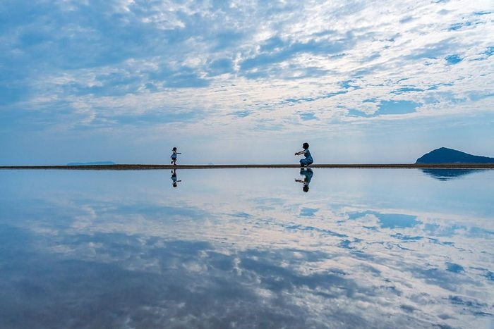  Một tạp chí du lịch đã gọi bãi biển Chichibugahama là "Hồ muối Uyuni của Nhật Bản", so sánh nơi đây với địa điểm du lịch nổi tiếng thế giới ở Bolivia, nơi bầu trời được phản chiếu trong một "tấm gương tự nhiên đầy nước". Các đài truyền hình quốc gia bắt đầu phát sóng các phóng sự về điểm đến hẻo lánh này và Chichibugahama trở thành địa điểm phải ghé thăm trên đảo Shikoku. Ảnh: Uesugi Kotetsu. 